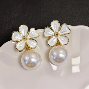 Close-up of white enamel flower and lustrous pearl on a vintage gold stud earring.