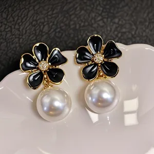 Macro view of exquisite black enamel flower earrings with elegant white pearl drops