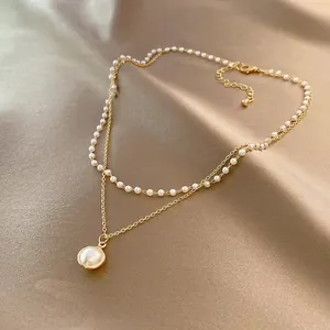 Detailansicht einer doppellagigen Halskette mit eleganten Perlenimitaten und Goldkette.