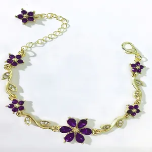Dettaglio di bracciale floreale dorato con petali in cristallo viola e piccoli fogliami