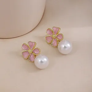 Close-up of elegant French vintage pink enamel flower and white pearl stud earrings