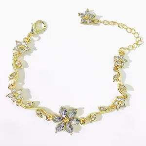 Dettaglio ravvicinato di un bracciale dorato con fiori e foglie e strass di cristallo