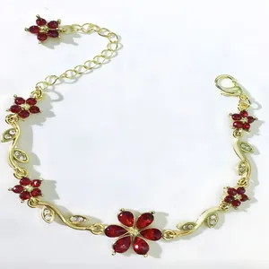 Dettaglio di un elegante bracciale dorato con cristalli floreali rossi e motivi a foglia lucenti