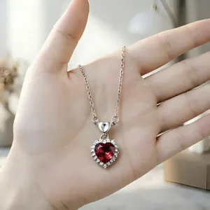 Primo piano di un'elegante collana con ciondolo a cuore in argento con gemma rossa.