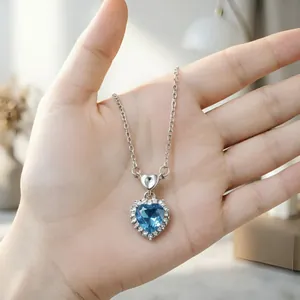 Dettaglio ravvicinato di una collana con ciondolo a cuore in cristallo blu tenuta in mano