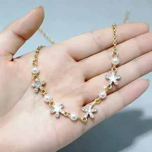 Elegante collana di perle dorate con ciondoli a fiore di strass sulla mano