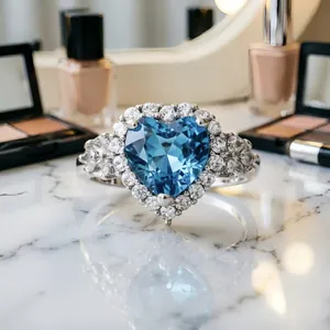 Dettaglio ravvicinato di un anello d'argento con una gemma blu a forma di cuore.