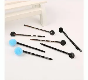 Gedetailleerde weergave van DIY-haarspeldaccessoires met blauwe pompons en zwarte cirkels