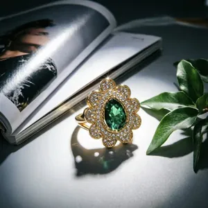 Lussuoso anello d'oro con gemma verde a goccia e alone floreale di cristallo