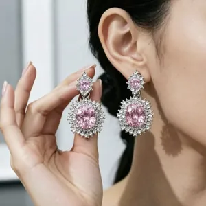 Dettaglio di orecchini pendenti di lusso con gemma rosa e pavé di diamanti su modella.