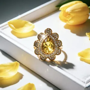 Primo piano di un anello di lusso in oro con gemma gialla a forma di pera e cristalli