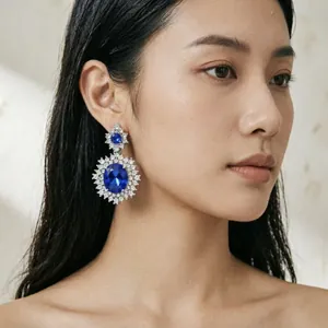 Primo piano di lussuosi orecchini a goccia con grandi gemme blu indossati da modella