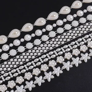 Macro view of various white ABS pearl chains in star, flower, and teardrop shapes for DIY.