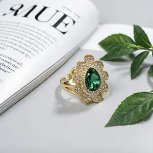 Primo piano anello oro lusso con pietra verde a goccia e dettagli pavé fiori