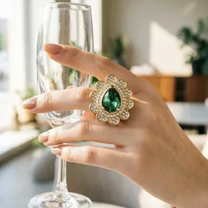 Primo piano di un anello di lusso con pietra verde a goccia e cristalli scintillanti.