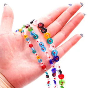 Macro view of colorful millefiori glass beads with heart patterns displayed on a hand