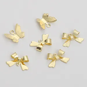 Vista detallada de dijes de mariposa y lazo bañados en oro de 14K para creación de joyas