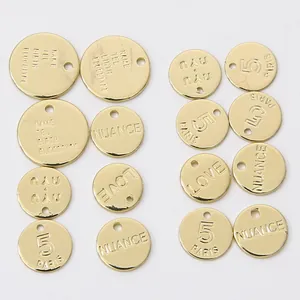 Close-up of 14K gold plated copper pendants with various engraved words and numbers.