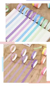 Detailed view of colorful washi tape strips applied to a grid notebook and wooden table
