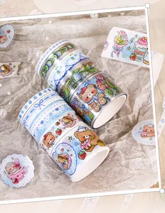 Close-up view of cute cartoon bear and floral washi tape rolls for scrapbooking and DIY crafts