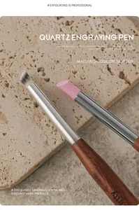 Close-up of dual-head quartz nail engraving pen with wooden handle on stone surface.