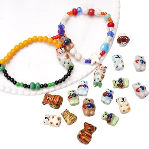 Detailed view of hand-painted ceramic animal beads in cat and bear shapes for DIY jewelry