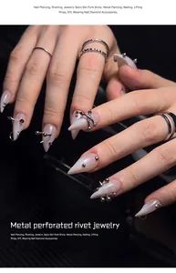 Close-up of stainless steel nail piercing rivets and jewelry on white pointed nails
