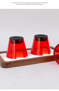 Detailed view of two red transparent nail phototherapy light shields on a wooden tray