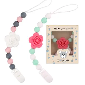 Detalle de sujetachupetes de silicona con cuentas de rosa y caja de regalo