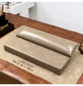 Set de reposabrazos profesional de cuero para manicura sobre una alfombrilla texturizada de salón