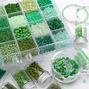 Variedad de cuentas de vidrio verde en caja de almacenamiento y viales para joyería DIY