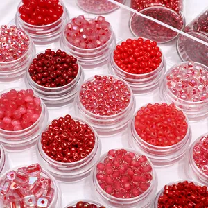 Close-up of various red and pink glass beads in clear plastic storage containers