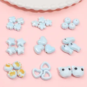 Assorted light blue ceramic beads in heart, star, and animal shapes for DIY jewelry making.