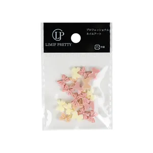 Pastel pink and cream resin bowknot nail art charms for DIY manicures in retail packaging