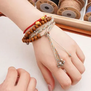 Handmade braided cotton thread bracelet with wooden beads and charms on the wrist
