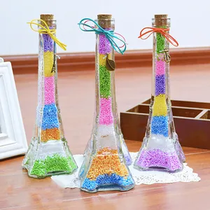 Three Eiffel Tower shaped glass bottles filled with vibrant colorful foam beads for DIY crafts