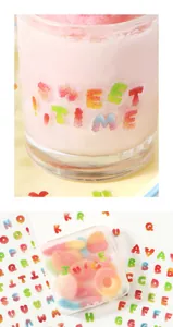 Nahaufnahme von Regenbogen Alphabet Aufklebern mit Gummibärchen Textur auf Glas.