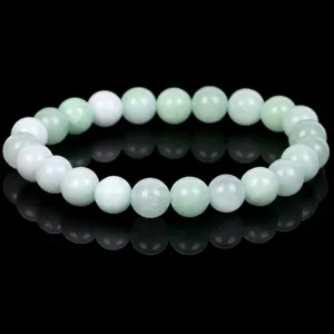 Detailed view of polished light green natural stone beads on a reflective surface