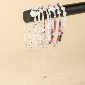 Close-up of shell and gemstone beaded bracelets hanging on a black display bar.