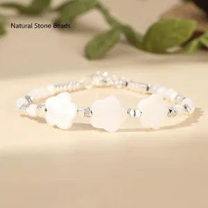 Macro view of white flower shell and jade beads bracelet detail against a soft background