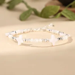 Close-up of white star shell beads and silver metal spacers on a handmade bracelet