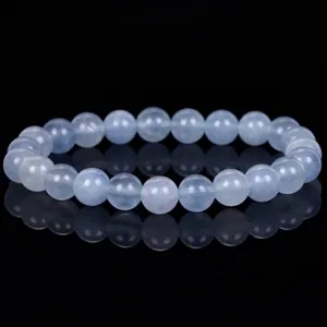 Close-up of polished light blue aquamarine beads on a reflective black surface bracelet