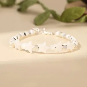 Close-up of elegant white star-shaped shell beads and silver cube spacers on a delicate bracelet