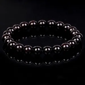 Detailed shot of a polished dark garnet crystal bead bracelet with mirror reflection