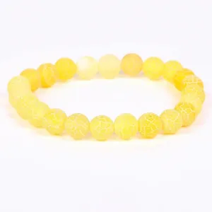 Detailed view of yellow weathered stone beads with intricate white web-like texture