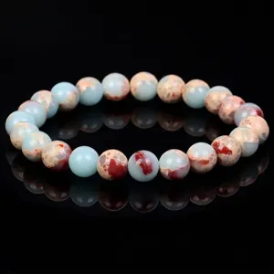 Detailed view of natural amazonite and red jasper beaded bracelet on black surface