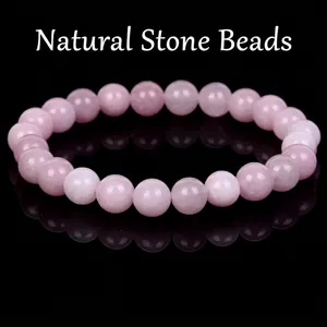Close-up macro view of a polished pink natural stone beaded bracelet on black surface
