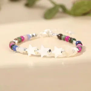 Detailed view of handmade beaded bracelet with white shell star charms