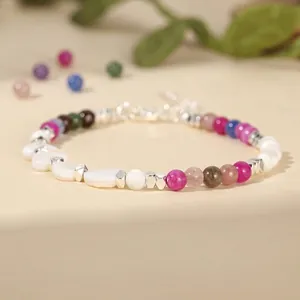Close-up detail of colorful natural stone and white shell beaded bracelet with silver spacers