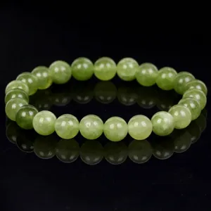 Macro view of a natural green jade bead bracelet on a reflective black background